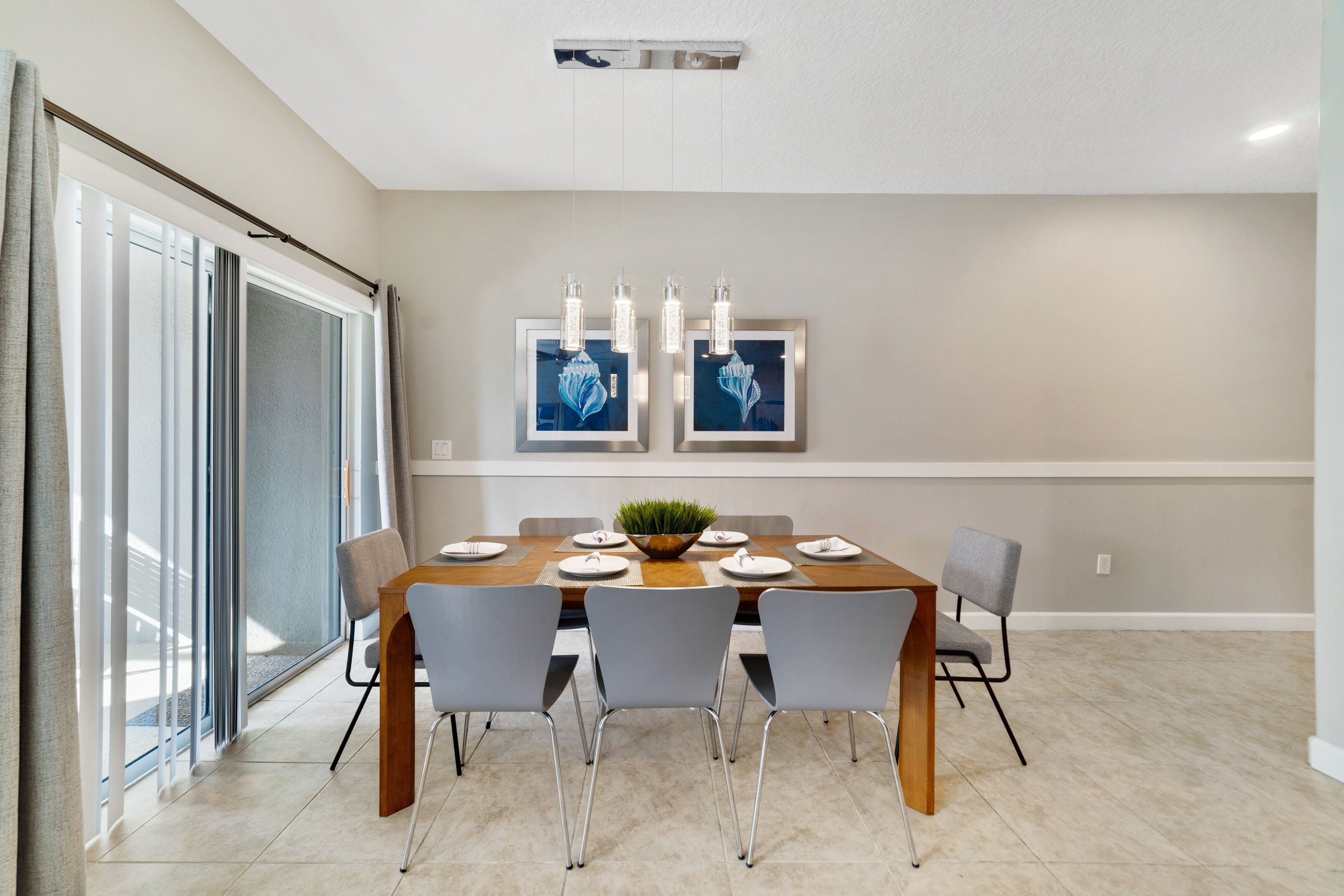 A modern dining room with a rectangular table, six chairs, and a central plant.