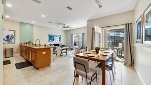 A spacious kitchen with a dining area, a ceiling fan, and a view to the outdoors. - Star Hideaway At Storey Lake By Shine Villas 4 Bedroom Townhouse (Kissimmee)