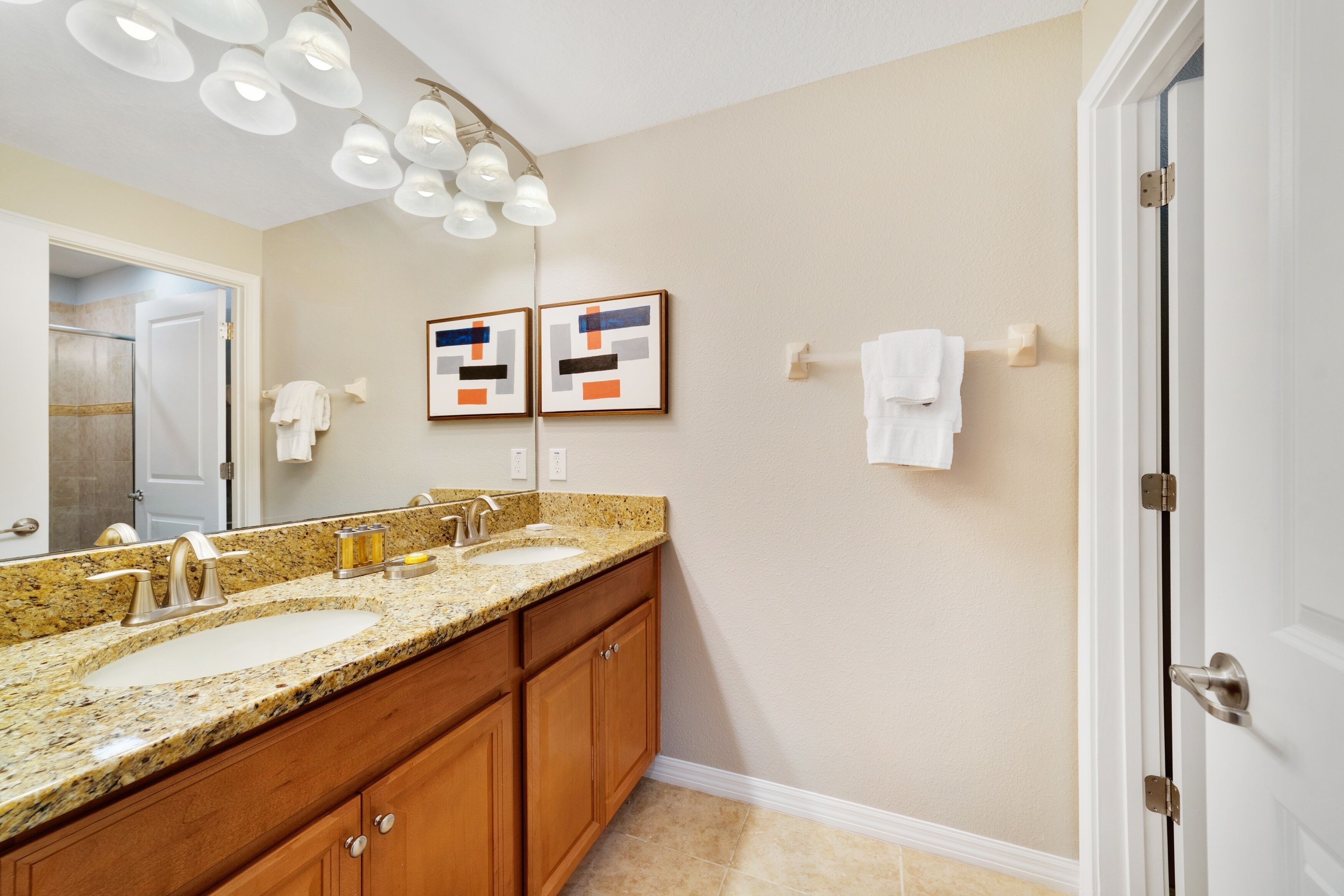 A bathroom with two sinks, wooden cabinets, a large mirror, and a ceiling light fixture.