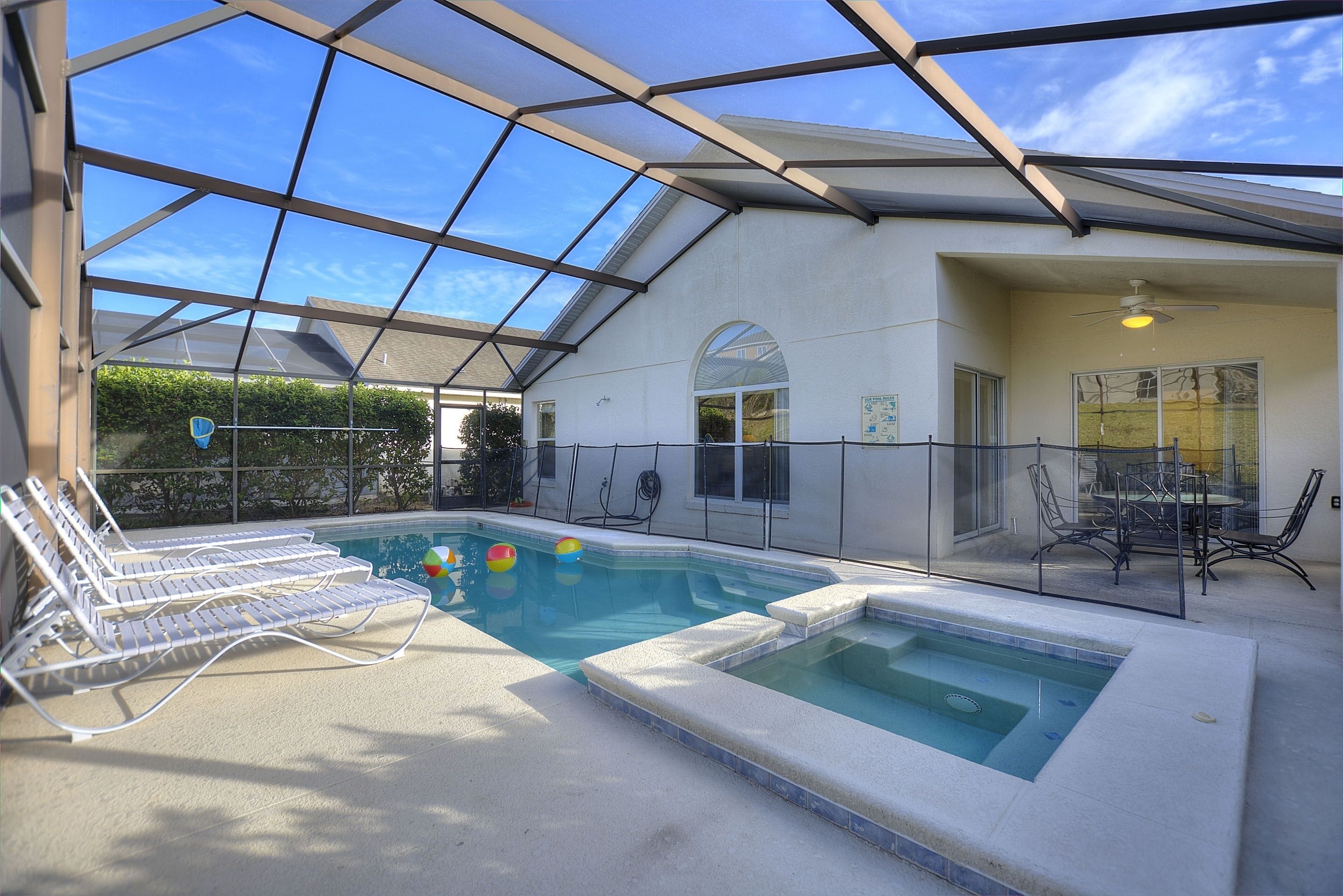 An indoor swimming pool with clear glass walls, a separate hot tub area, and lounge chairs.
