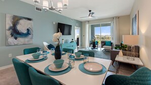 Un comedor moderno con sillas color turquesa, una mesa blanca y decoración azul y blanca.