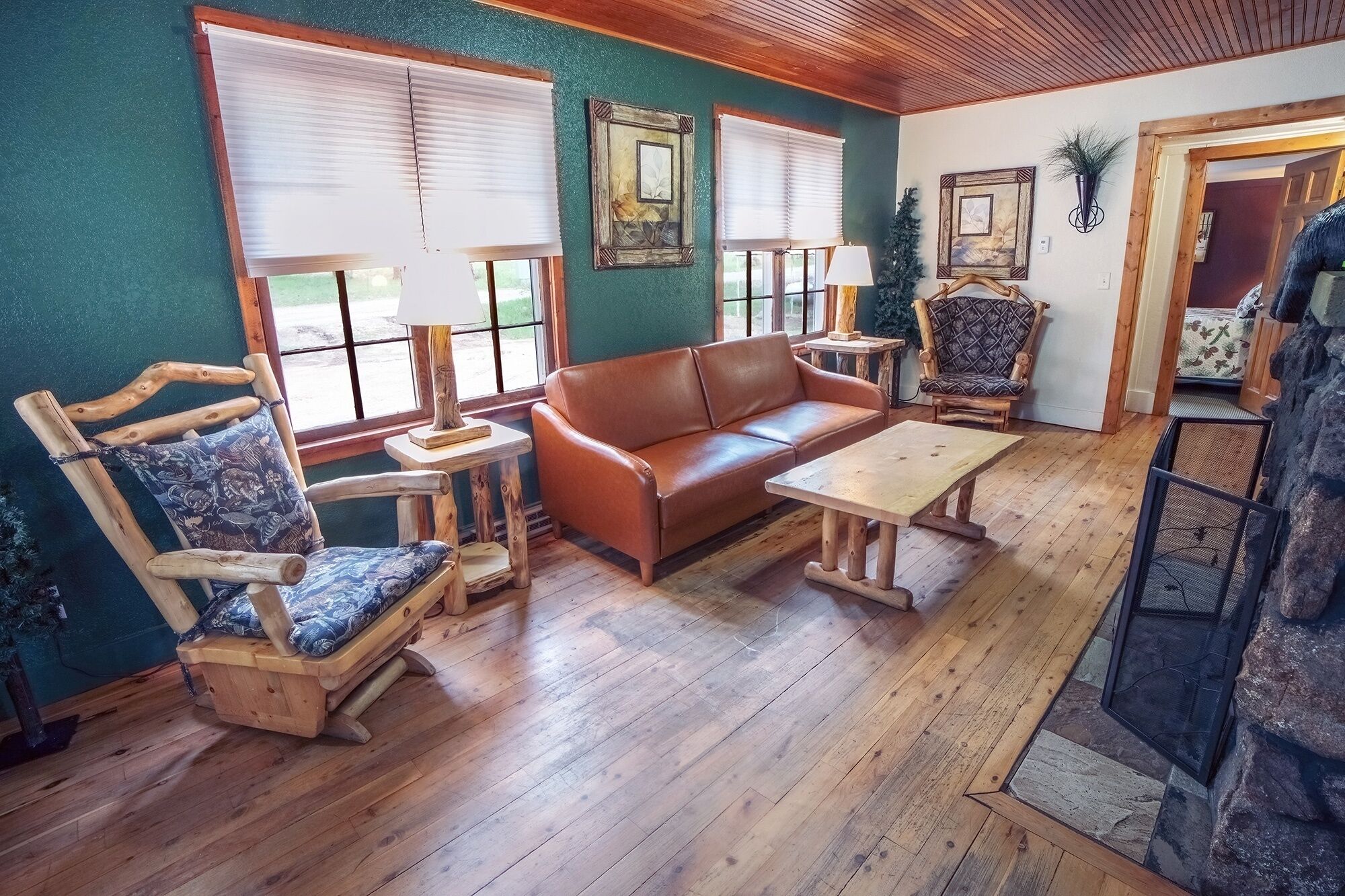 Una sala de estar acogedora con un sofá de cuero marrón, sillas de madera, una mesita y una chimenea de piedra.