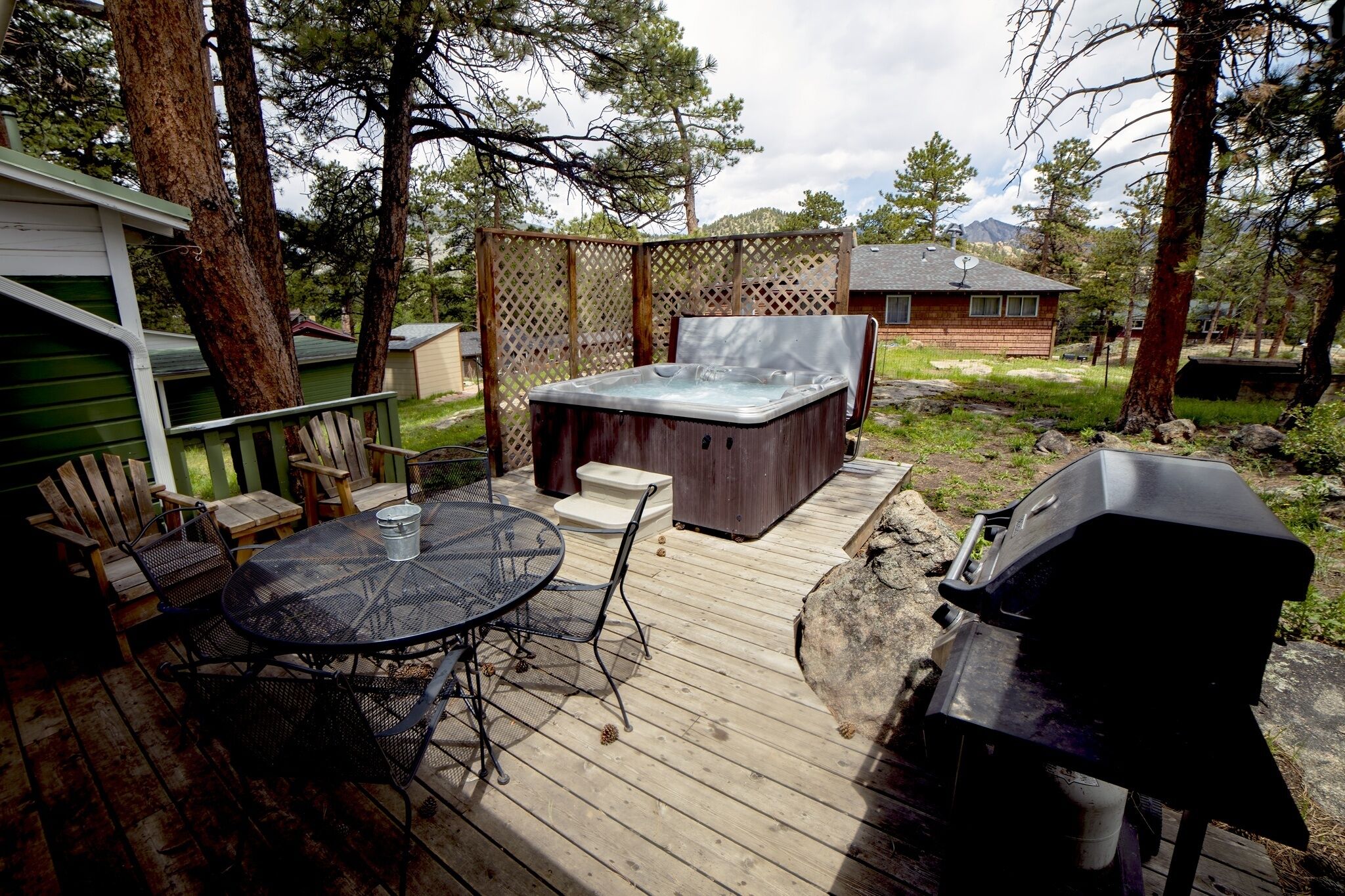 A deck with a hot tub, a grill, and outdoor seating.