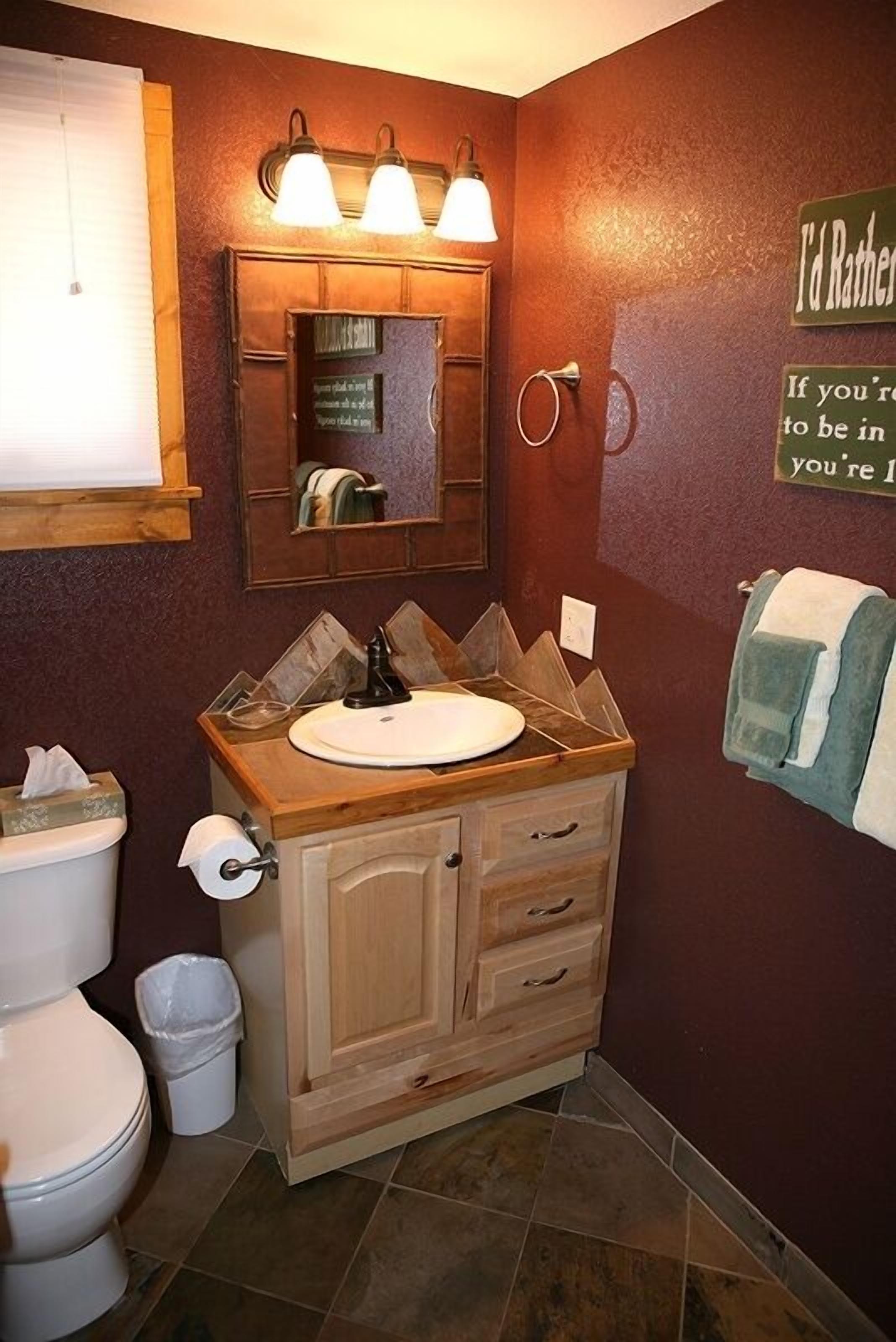 Un bagno con un mobile vanitario in legno, uno specchio e un portascopevoli.