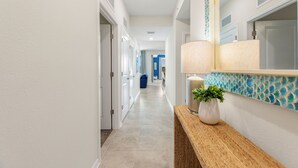 A hallway with a wooden console table, a potted plant, and a mirror with a decorative backsplash. - Serenity Haven, Bliss, Storey Lake By Shine Villas 2 Bedroom Condo (Kissimmee)