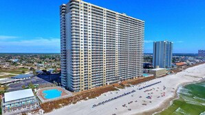 A high-rise hotel with multiple floors, a pool, and a beach area with umbrellas and sun loungers. - Tidewater Beach Luxury Penthouse With Resort Amenities and a View! (Panama City Beach)