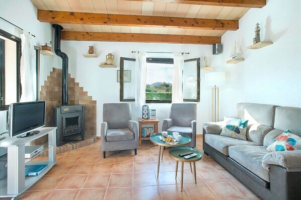Una sala de estar acogedora con chimenea, asientos cómodos, televisor y vistas al exterior.