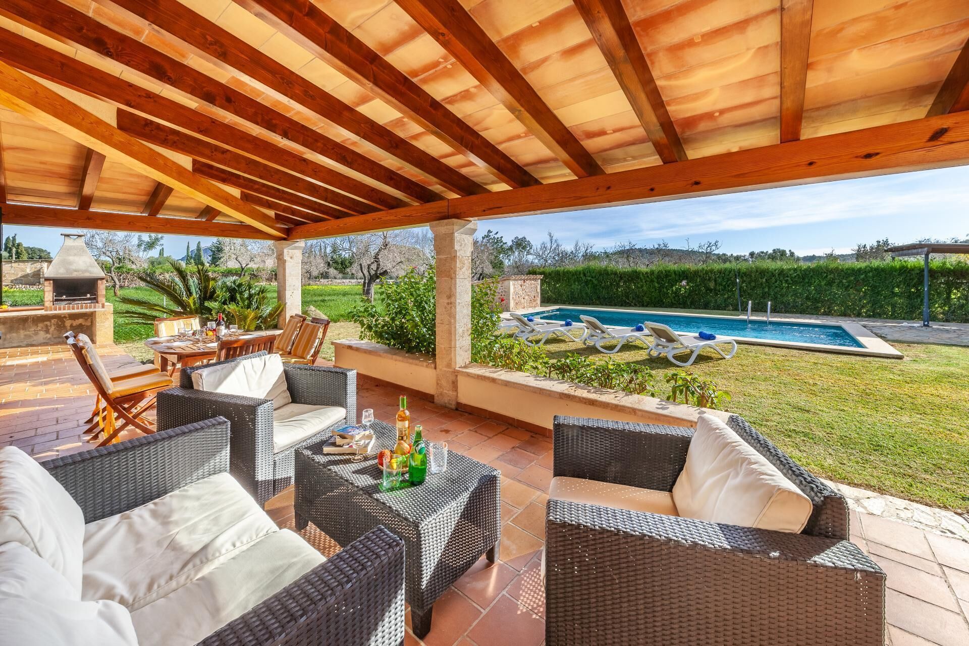 An outdoor patio with wicker furniture, a pool, and a barbecue area.