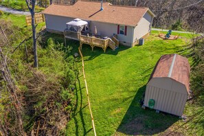 A house with a covered patio, a fenced yard, and a shed.