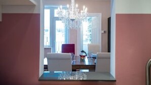 Un coin repas agrémenté d’un lustre, d’une table dressée pour deux personnes et offrant une vue sur l’extérieur grâce à une grande fenêtre.
