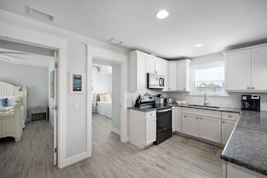 A modern kitchen with white cabinetry, a built-in oven, and a microwave.