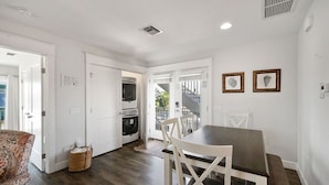 Una cocina moderna con electrodomésticos integrados, una zona de comedor con mesa y sillas, y vistas al exterior.