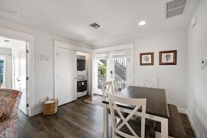 A modern kitchen with built-in appliances, a dining area with a table and chairs, and a view of the outside.