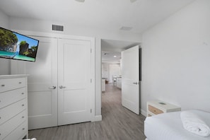 A hotel room with a bed, a TV, a wardrobe, and a desk.