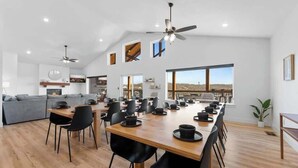 A spacious dining area with a long wooden table, black chairs, and a ceiling fan. - Lake View|Pools·Hot Tub·Sauna|Game&Theater Rm·18 (Indian Point)