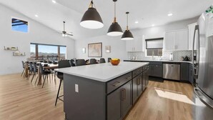 A modern kitchen with a large island, pendant lights, and stainless steel appliances. - Lake View|Pools·Hot Tub·Sauna|Game&Theater Rm·18 (Indian Point)