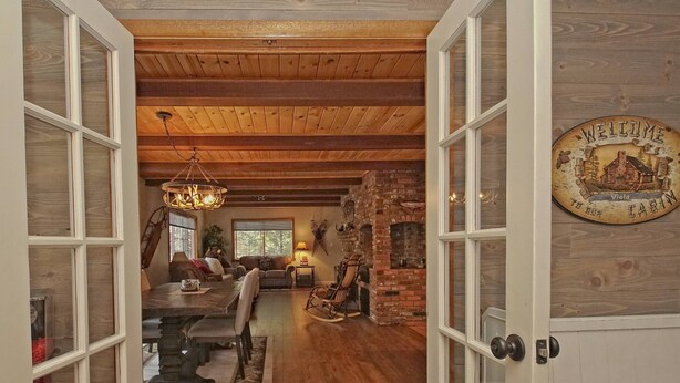 L’intérieur d’un chalet rustique comprend un coin repas, une cheminée et une pancarte sur laquelle on peut lire : « Bienvenue au chalet Viola ».