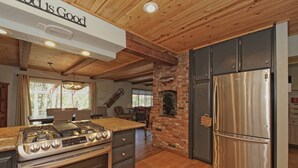 Une cuisine équipée d’un réfrigérateur en acier inoxydable, d’une cuisinière à gaz et de meubles de rangement en bois.