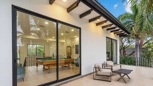 A modern indoor pool area with a glass wall, pool table, and seating.