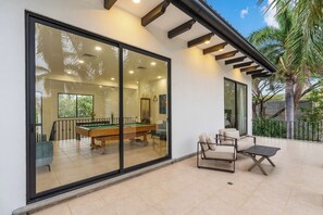 A modern indoor pool area with a glass wall, pool table, and seating.