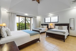 A hotel room with two beds, a ceiling fan, and large windows with curtains.