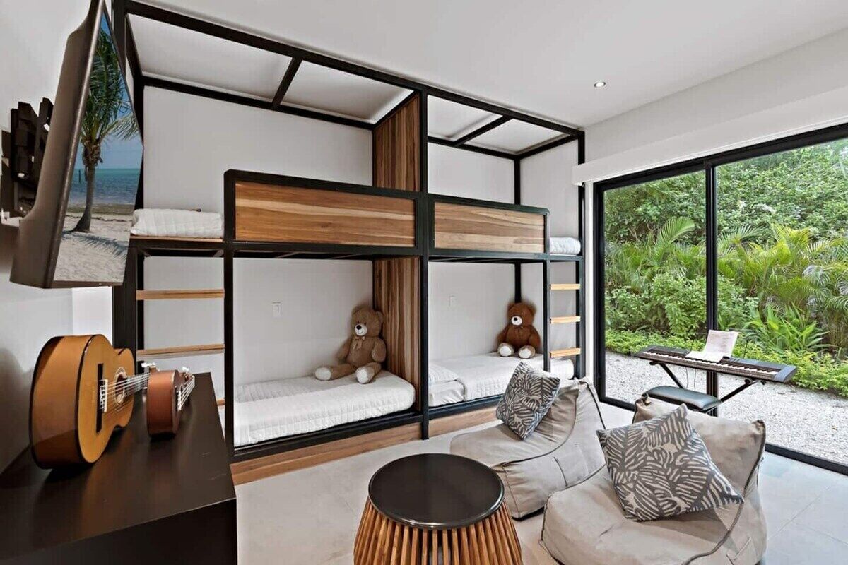 A modern room with bunk beds, a sofa, a guitar, and a view of greenery.