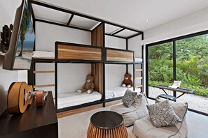 Ein modernes Zimmer mit Etagenbetten, einer Schlafcouch, einer Gitarre und Blick auf Grünflächen.