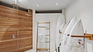 A modern bathroom with a wooden panel wall, a shower, and surfboards mounted on the wall.
