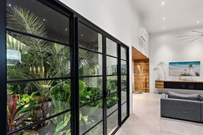 Un salón moderno con un separador de vidrio, un sofá gris y una pared de acento de madera.
