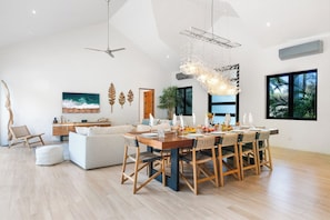 A modern living room with a dining area, wooden flooring, and large windows. - Luxury property with private pool, Beach Club Access, daily housekeeping, concierge services (Reserva de Golf 84, Hacienda Pinilla)
