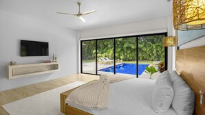 Une chambre moderne avec un grand lit, une télévision et une vue sur une piscine.