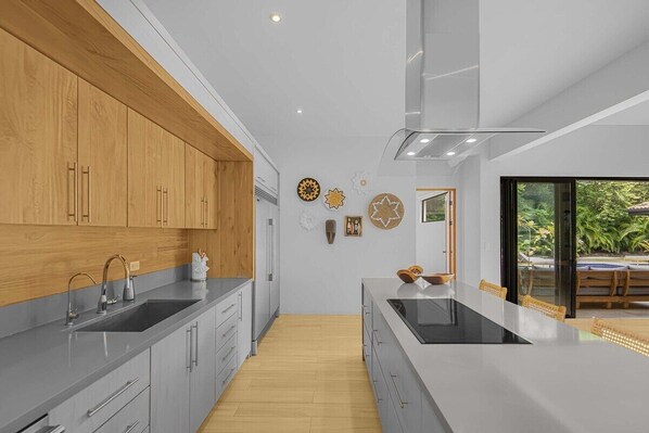 A modern kitchen with wooden cabinets, a large island, and a view of the outdoors.