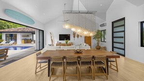 Un intérieur moderne comprenant un coin repas, une grande fenêtre et une vue sur une piscine.