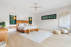 A modern bedroom with a wooden bed, a ceiling fan, a large window with a view, and a white rug. - Luxury property with private pool, Beach Club Access, daily housekeeping, concierge services (Reserva de Golf 84, Hacienda Pinilla)