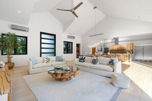 A spacious living area with a high ceiling, a ceiling fan, a dining area, and a kitchen.