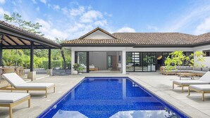 Une maison moderne dotée d’une piscine, d’un espace salon extérieur et d’un patio couvert.