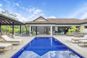 Uma casa moderna com piscina, área de estar externa e um espaço de varanda coberto.