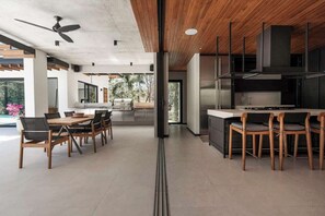 A modern kitchen with a central island, wooden chairs, and a dining area with a table and chairs.