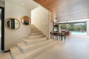 A modern interior with a staircase, dining area, and a view of a swimming pool. - Villa Solana (Tamarindo)