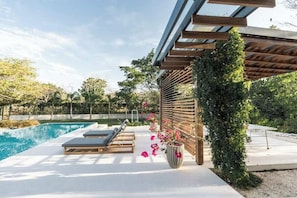 Zona de piscina amb gandules, una pèrgola i una planta en test.