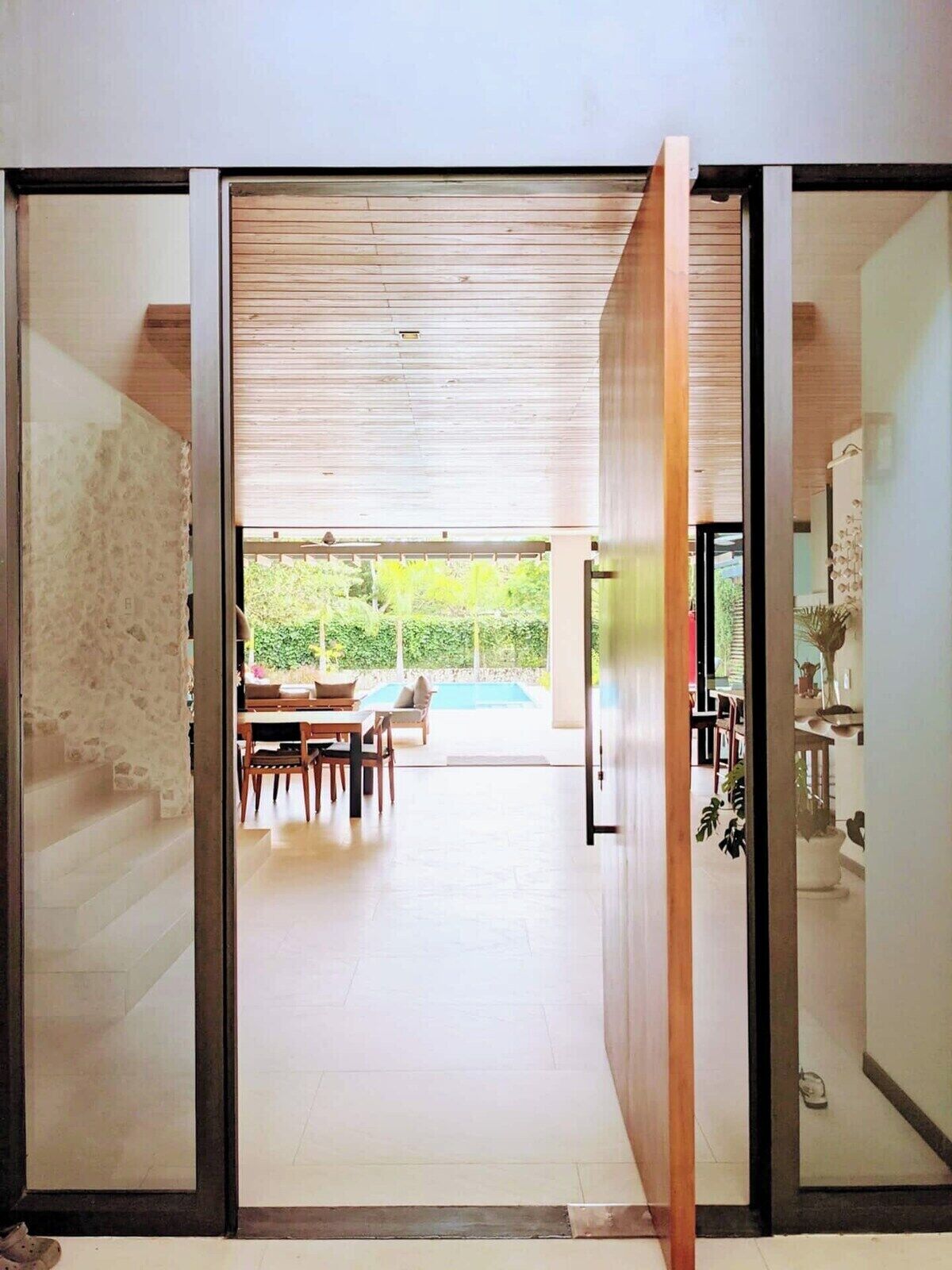 A modern interior with a sliding door leading to a dining area and a pool.