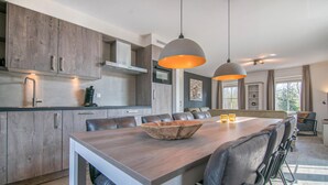 A modern kitchen with wooden cabinets, a large dining table, and pendant lighting. - 4 bedroom gorgeous home in Den Ham (Den Ham)