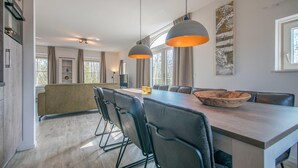 A modern kitchen with a dining area, featuring a large island, pendant lights, and a view of the outdoors. - 4 bedroom gorgeous home in Den Ham (Den Ham)