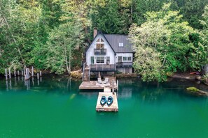 Ein Haus mit einem Steg, der in einen See führt, umgeben von dichtem Wald.