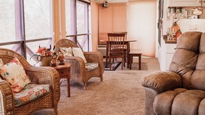 A cozy living room with wicker furniture, a brown sofa, and a dining table.