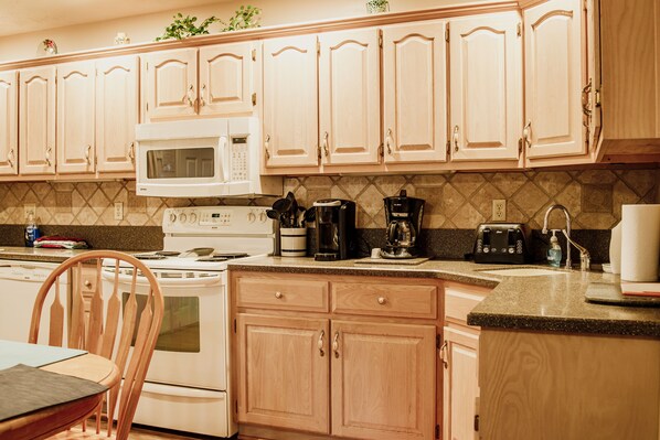 A kitchen with wooden cabinets, a microwave, a stove, a coffee maker, and a toaster.