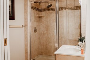 A bathroom with a glass-enclosed shower, a white sink, and a decorative tile border.