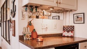 A kitchen with a granite countertop, a coffee maker, a pumpkin decoration, and a welcome sign.