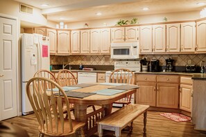 A kitchen with wooden cabinets, a microwave, a stove, and a dining table with chairs.