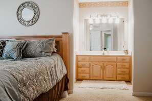 A bedroom with a bed, a dresser, a mirror, and a light fixture.